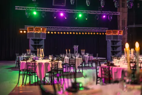 Round laid tables in a hall with coloured light